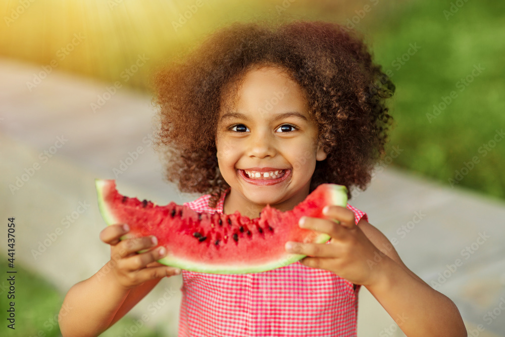 Foto de Funny Black kid eating watermelon outdoors in hot summer