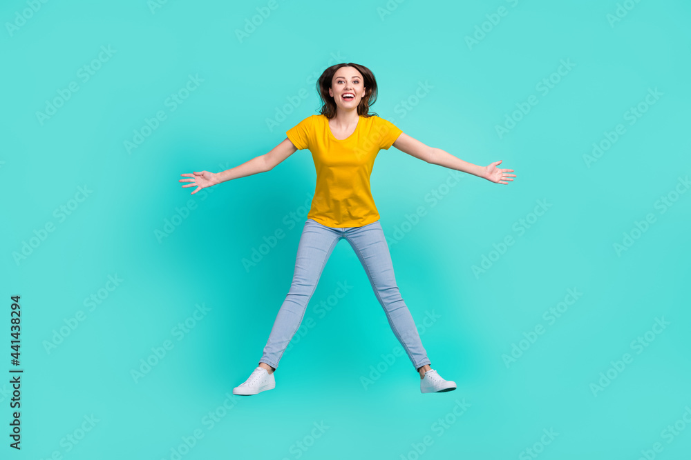 Full body photo of joyful young lady jump wear yellow t-shirt jeans isolated on teal color background Full body photo of joyful young lady jump wear yellow t-shirt jeans isolated on teal color background