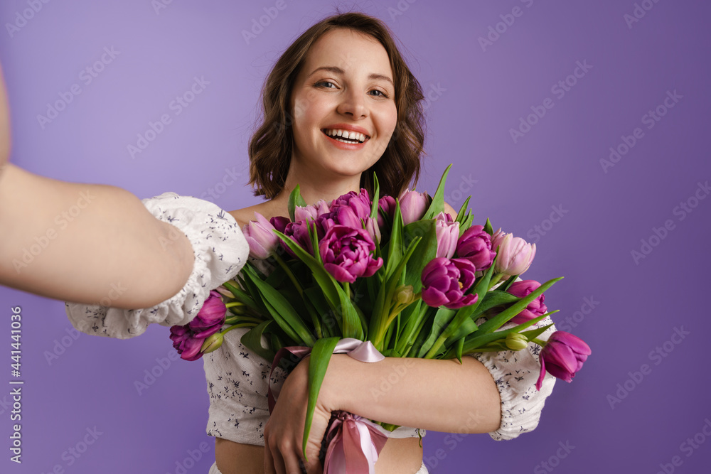 White smiling woman taking selfie while holding tulips White smiling woman taking selfie while holding tulips