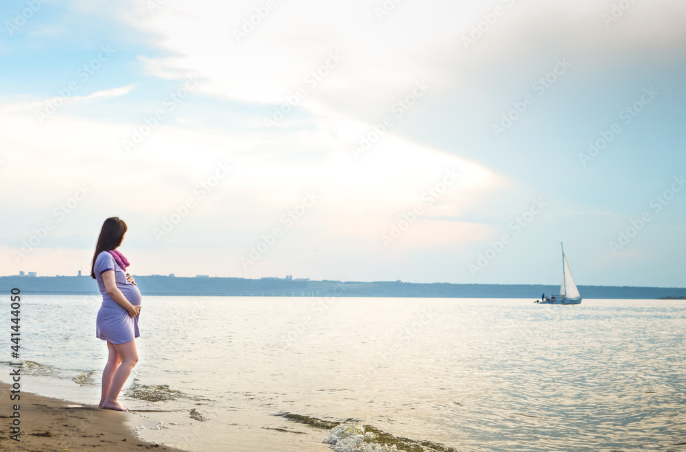 A pregnant girl escorts a guy to a swim near the shore