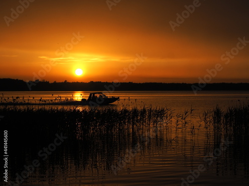 Motorboat and sunset. Vacation time and travel. Speed ​​and wind. Sultry evening and lake © Gunars