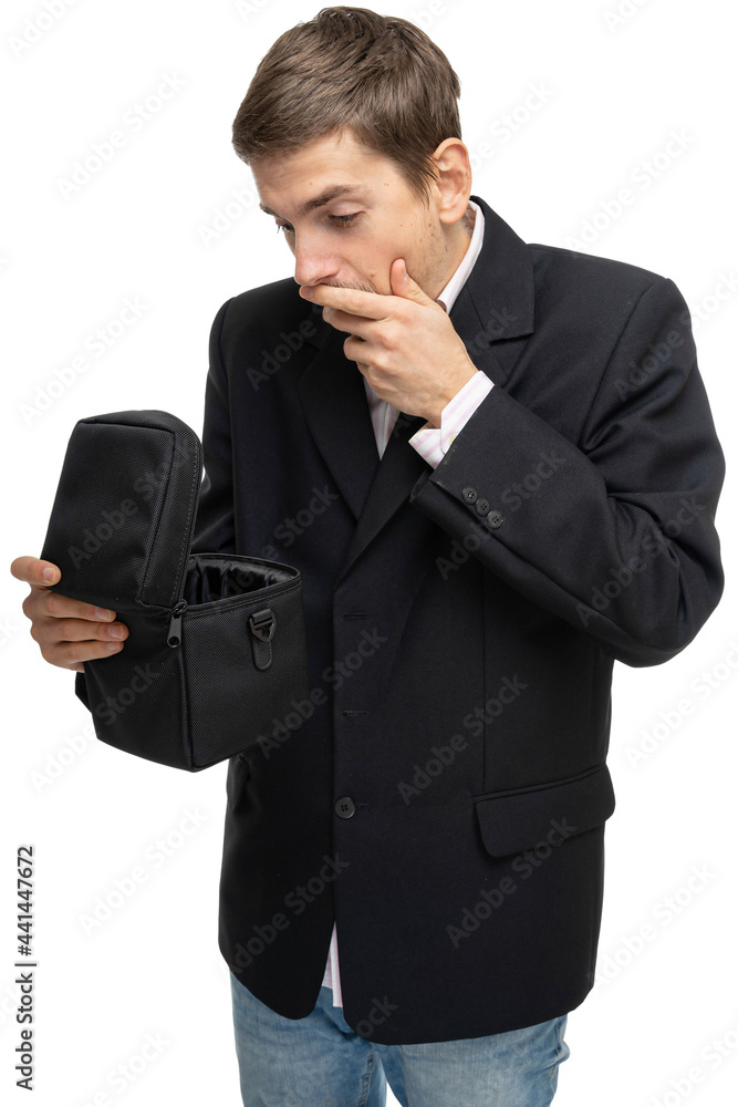 Young handsome tall slim white man with brown hair is surprised looking into small black case in black blazer isolated on white background Young handsome tall slim white man with brown hair is surprised looking into small black case in black blazer isolated on white background