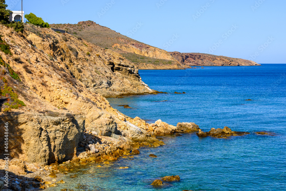 Rocky cliffs on the coast of Piso Livadi. Beautiful bay with blue ocean water. Paros, Greece