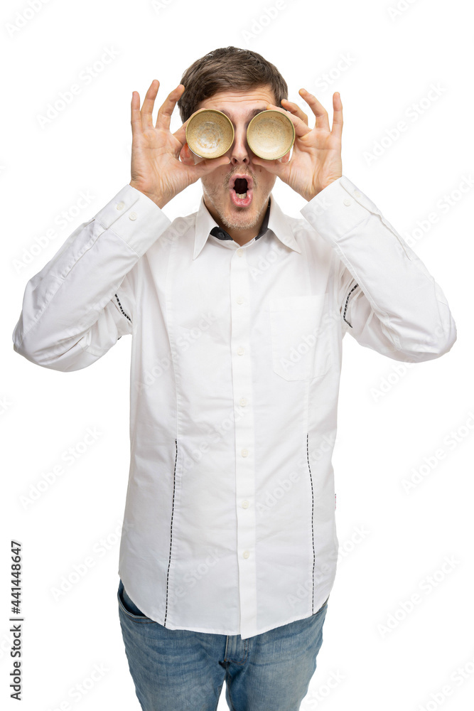 Young handsome tall slim white man with brown hair with two tea cups as his eyes in white shirt isolated on white background Young handsome tall slim white man with brown hair with two tea cups as his eyes in white shirt isolated on white background