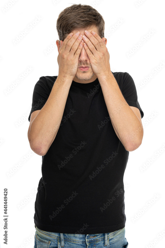 Young handsome tall slim white man with brown hair covering his eyes in black shirt in blue jeans isolated on white background Young handsome tall slim white man with brown hair covering his eyes in black shirt in blue jeans isolated on white background