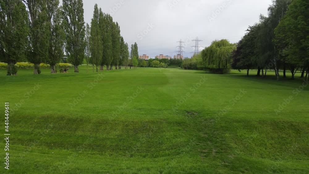 maintained lawn between rows of grown trees. Urban neighbourhood in background. Golf course in town maintained lawn between rows of grown trees. Urban neighbourhood in background. Golf course in town