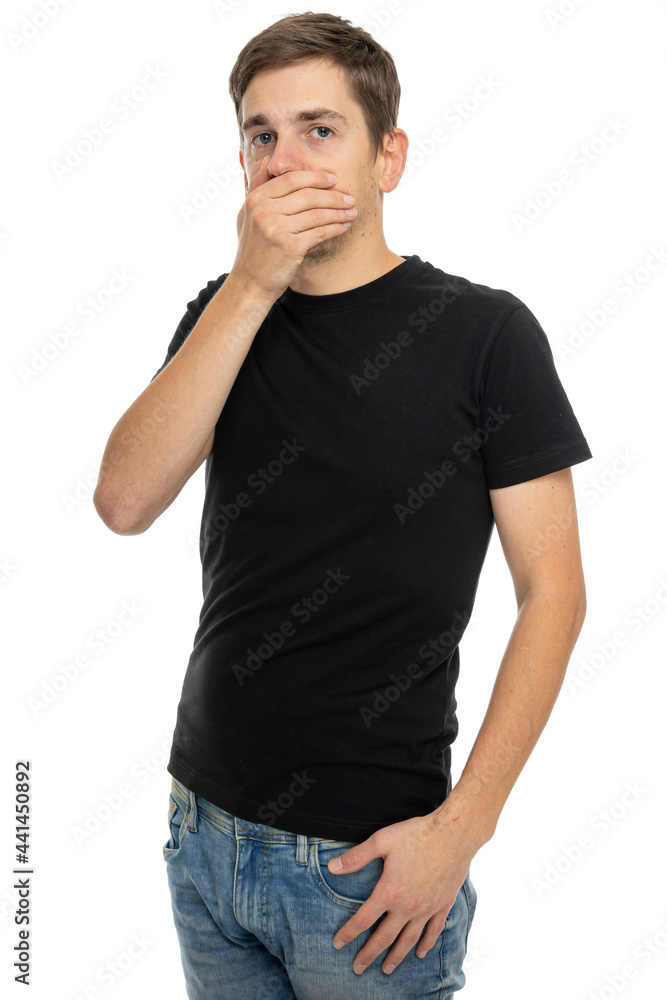 Young handsome tall slim white man with brown hair holding his mouth in black shirt in blue jeans isolated on white background Young handsome tall slim white man with brown hair holding his mouth in black shirt in blue jeans isolated on white background