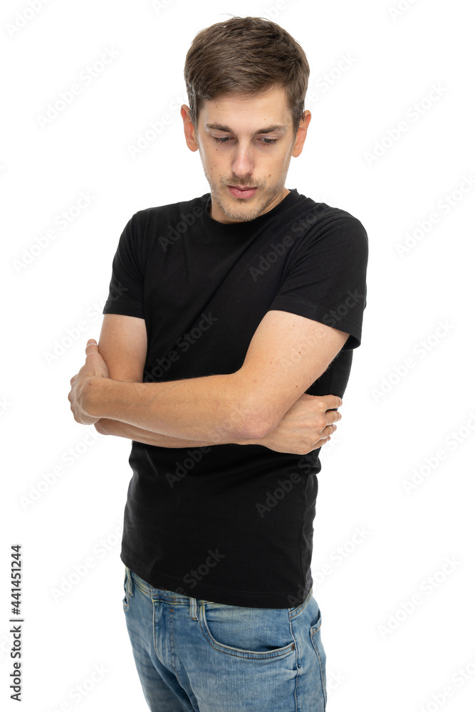 Young handsome tall slim white man with brown hair with folded arms looking down in black shirt in blue jeans isolated on white background Young handsome tall slim white man with brown hair with folded arms looking down in black shirt in blue jeans isolated on white background