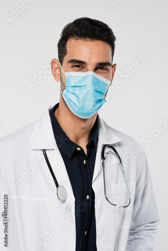 Arabian doctor with stethoscope looking at camera isolated on grey