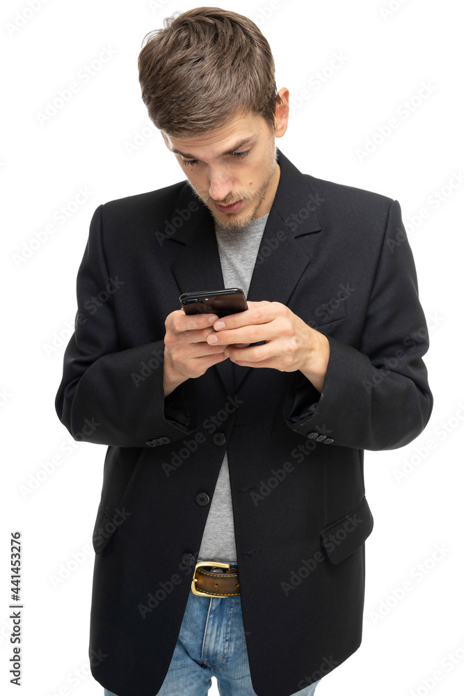 Young handsome tall slim white man with brown hair is looking to his mobile phone in black blazer isolated on white background Young handsome tall slim white man with brown hair is looking to his mobile phone in black blazer isolated on white background