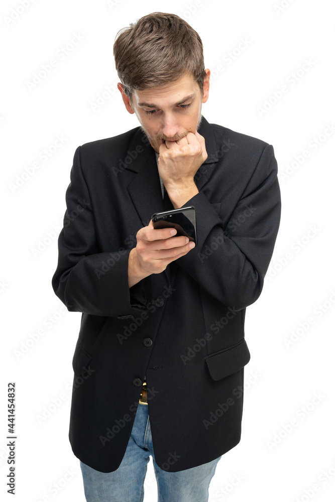 Young handsome tall slim white man with brown hair is anxiously looking to his mobile phone in black blazer isolated on white background Young handsome tall slim white man with brown hair is anxiously looking to his mobile phone in black blazer isolated on white background