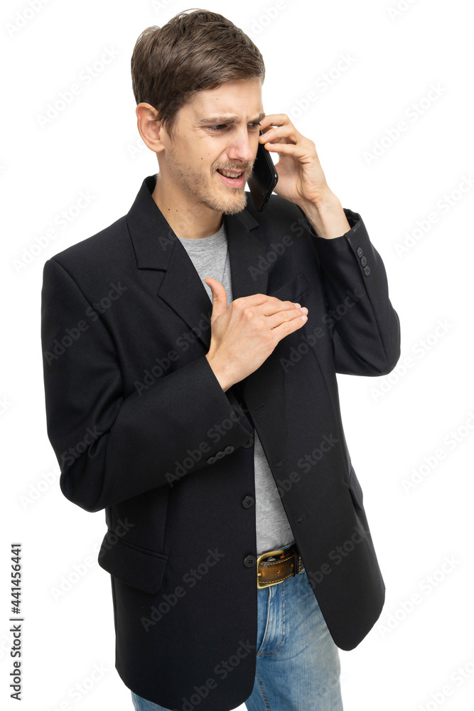Young handsome tall slim white man with brown hair is on the mobile phone looks unhappy in black blazer isolated on white background