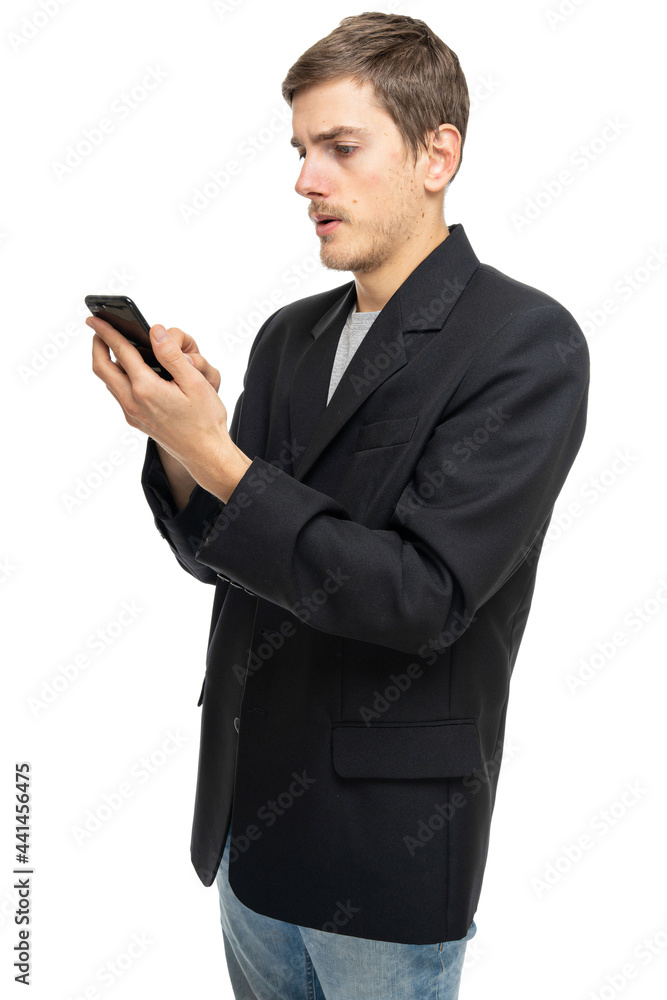 Young handsome tall slim white man with brown hair is looking to his mobile phone in black blazer isolated on white background Young handsome tall slim white man with brown hair is looking to his mobile phone in black blazer isolated on white background