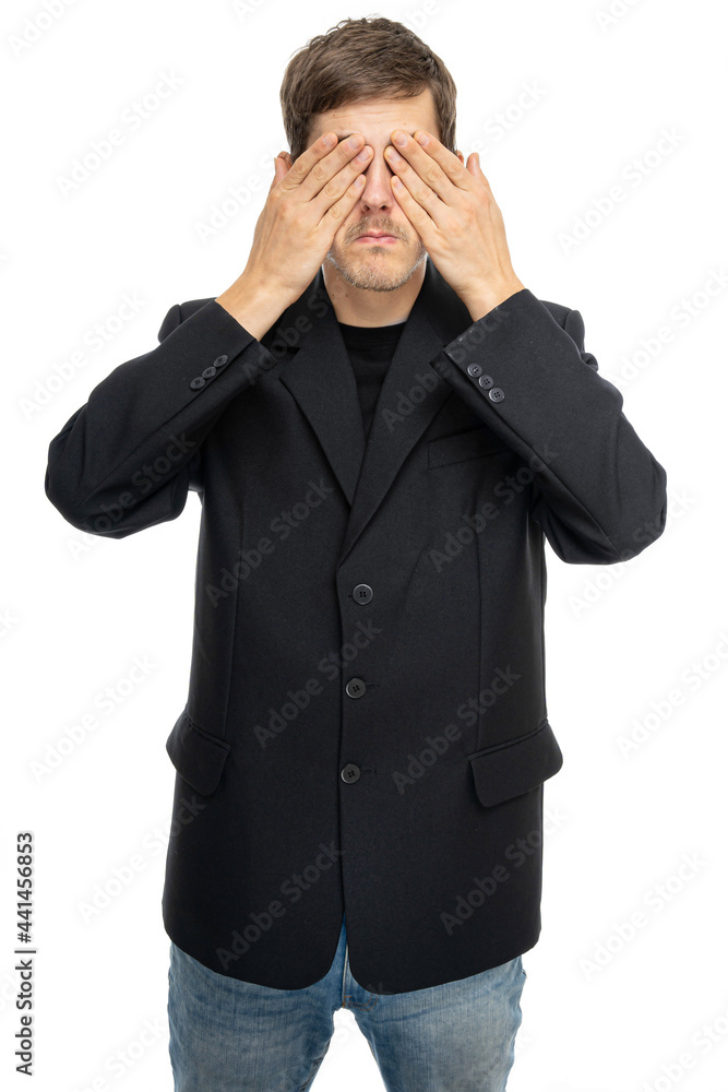 Young handsome tall slim white man with brown hair covers his eyes in black blazer in blue jeans isolated on white background Young handsome tall slim white man with brown hair covers his eyes in black blazer in blue jeans isolated on white background