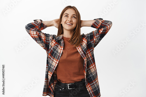 Relaxed girl hold hands behind head, lying and watching something up, looking at top with pleased facr while resting, relaxing on leisure time, white background photo