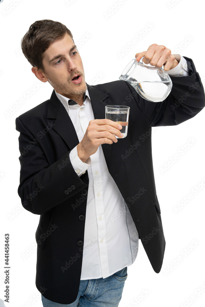 Young handsome tall slim white man with brown hair pouring water from glass pitcher into little glass in black blazer isolated on white background Young handsome tall slim white man with brown hair pouring water from glass pitcher into little glass in black blazer isolated on white background