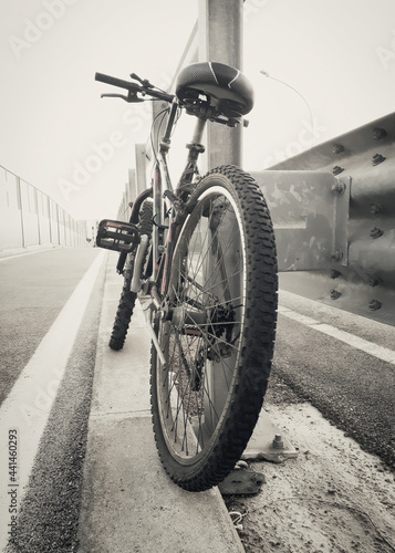 A cool mountain bike, shot from behind, laying against the guard rail of a street. Concepts: adventure, sport, exploring. 