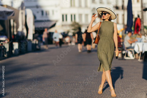 Woman with book and hat walking in the city