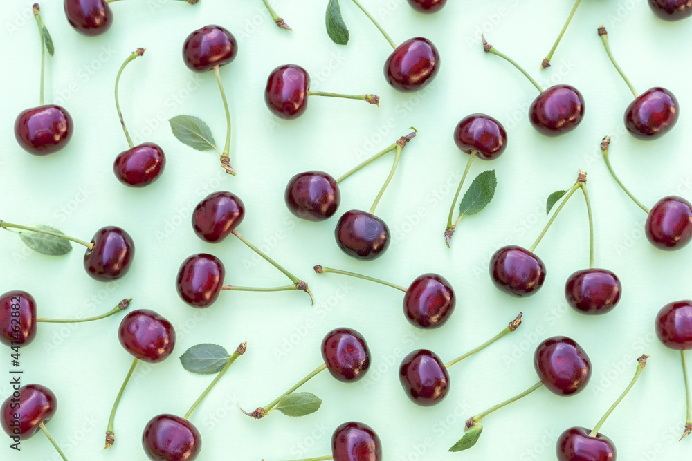 Cherry pattern. Flat lay of cherries and leaves on a soft green background. Food background. Cherries flat design. Top view, flat lay. Cherry pattern. Flat lay of cherries and leaves on a soft green background. Food background. Cherries flat design. Top view, flat lay.