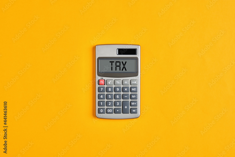 The word tax on calculator display with yellow background. Tax calculation, business finance The word tax on calculator display with yellow background. Tax calculation, business finance