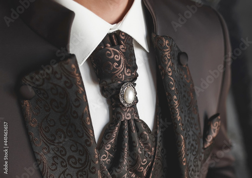 Luxurious brown men's suit with patterns and a tie, white shirt close-up
