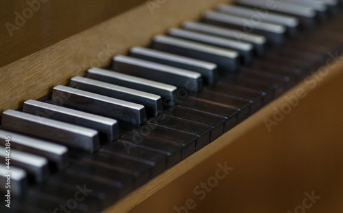 A Close up Photograph of a Antique Piano or Organ with Black Keys