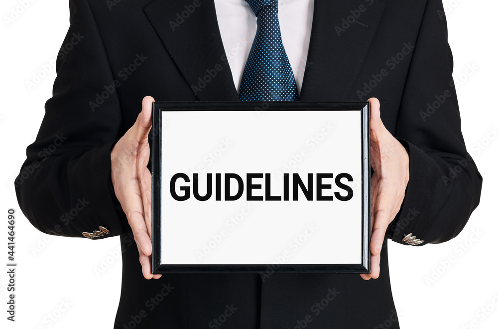 Businessman holds a signboard with the word guidelines on isolated white background. Business rules, standards or policies Businessman holds a signboard with the word guidelines on isolated white background. Business rules, standards or policies