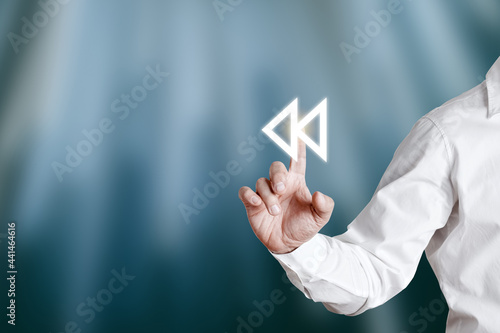 Businessman hand pressing rewind icon on a virtual display screen. photo