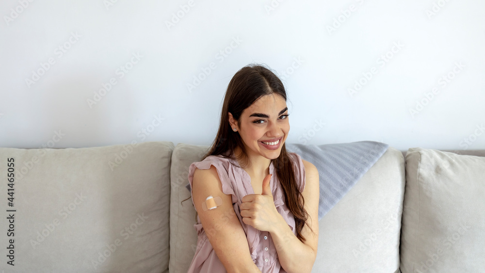 Happy vaccinated woman showing arm with plaster bandage after Covid-19 vaccine injection, posing over white background, smiling to camera. Young woman after vaccination. Virus protection. COVID-2019. Happy vaccinated woman showing arm with plaster bandage after Covid-19 vaccine injection, posing over white background, smiling to camera. Young woman after vaccination. Virus protection. COVID-2019.