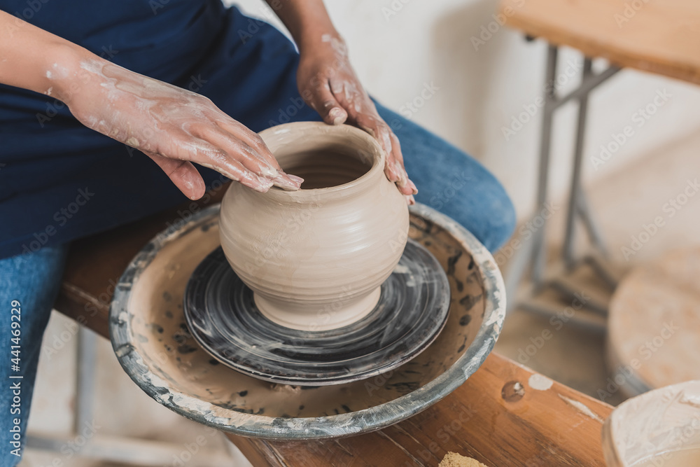 partial view of young african american woman modeling wet clay pot on wheel with hands in pottery partial view of young african american woman modeling wet clay pot on wheel with hands in pottery