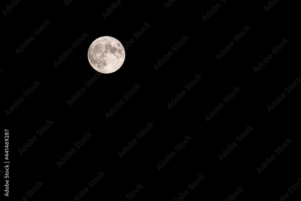 Strawberry full moon rising during summer night with dark black sky. Strawberry full moon rising during summer night with dark black sky.