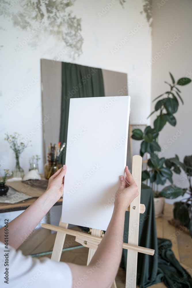 The artist places a white canvas on an easel. Hobbies, drawing. Preparing tools The artist places a white canvas on an easel. Hobbies, drawing. Preparing tools