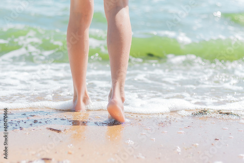 bare feet of a girl walk on the sand on the beach to sea water. summer vacation and travel concept.