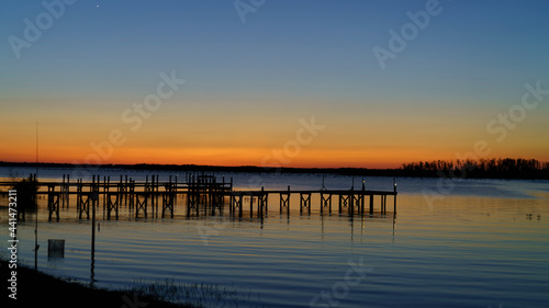 Fishing Pier Sunrise/Sunset Over Still Water mirroring a Vibrant Colored Sky.