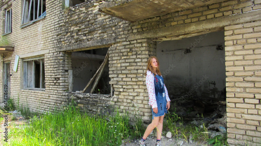 A young girl on the background of an abandoned building