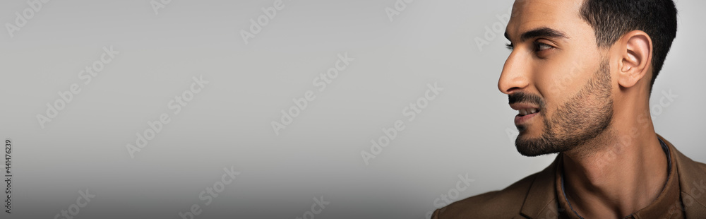 Obraz premium Side view of smiling muslim businessman on grey background, banner