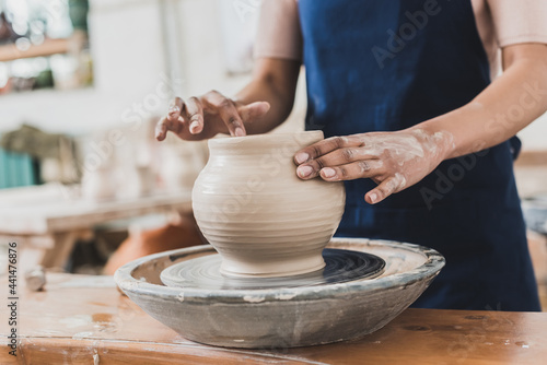 partial view of young african american woman modeling wet clay pot on wheel in pottery