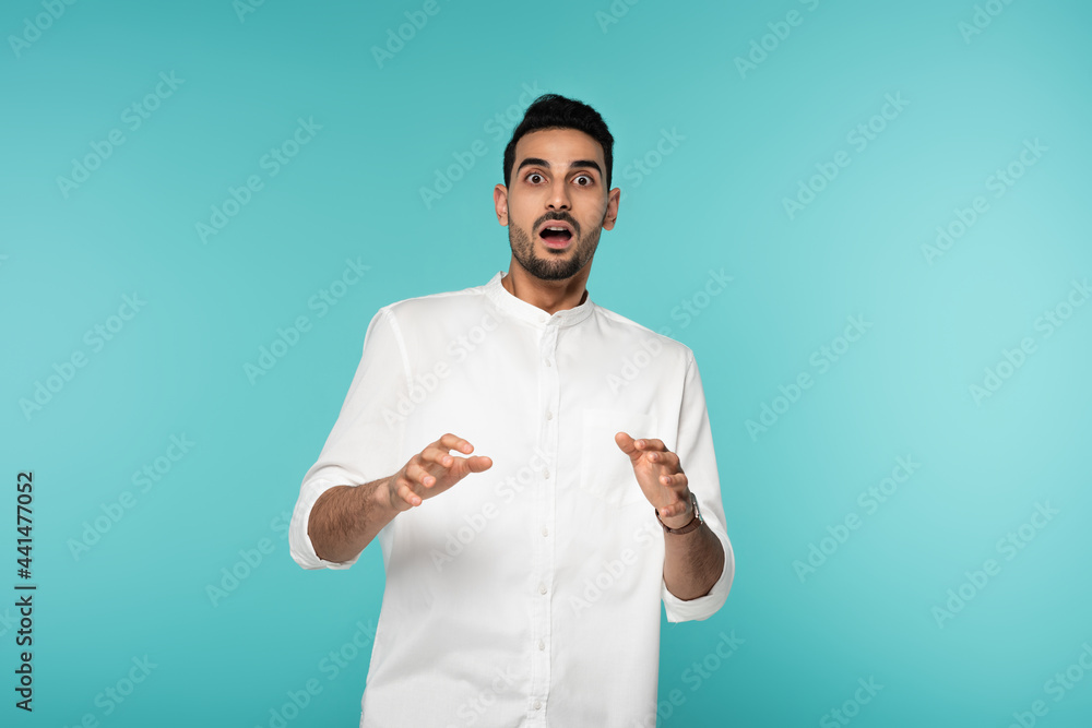 Scared muslim man looking at camera isolated on blue Scared muslim man looking at camera isolated on blue