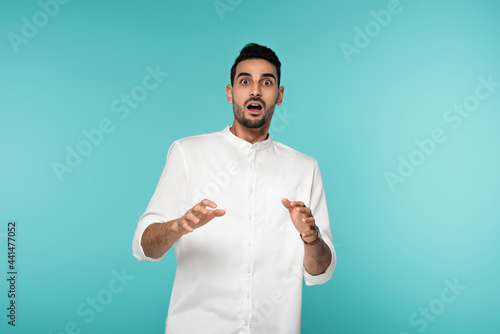 Scared muslim man looking at camera isolated on blue © LIGHTFIELD STUDIOS