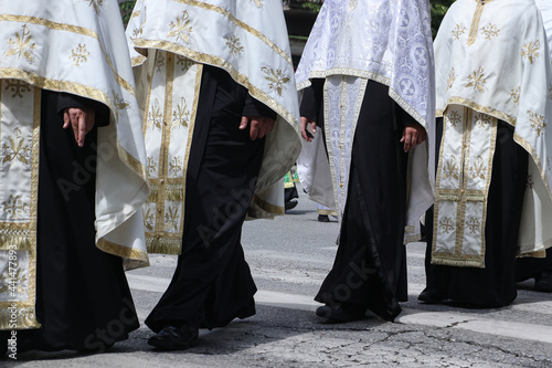Valokuva Group of orthodox priests in vestments walk in line crossing the street
