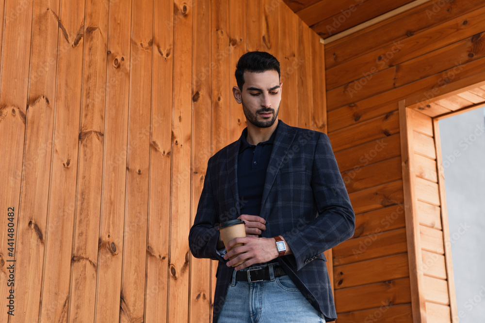 Muslim businessman with coffee to go looking at wristwatch outdoors Muslim businessman with coffee to go looking at wristwatch outdoors