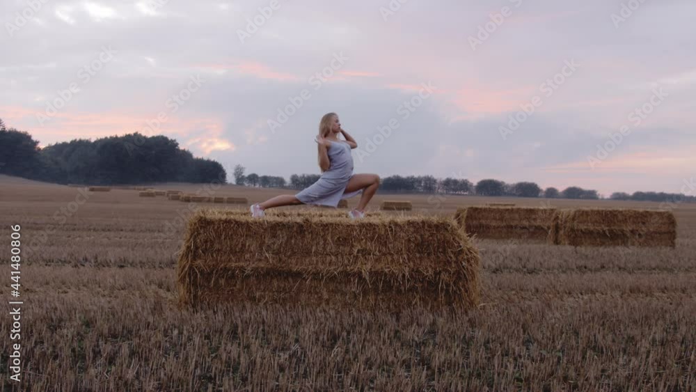 A Female Blonde Model Stretching on Top Of a Haystack A Female Blonde Model Stretching on Top Of a Haystack