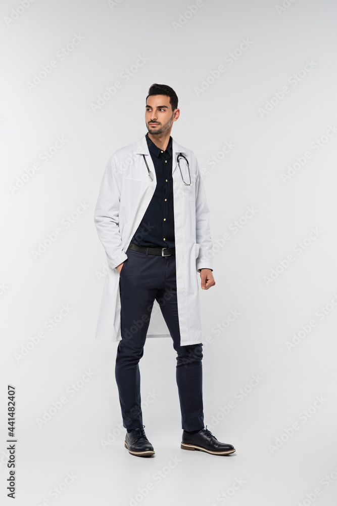 Arabian doctor in white coat looking away on grey background Arabian doctor in white coat looking away on grey background