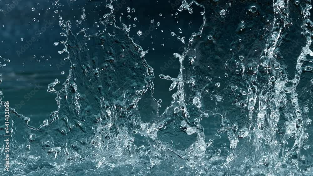 Super slow motion of splashing water isolated on blue background. Filmed on high speed cinema camera, 1000 fps.
