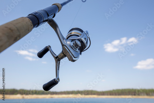 Fishing gear. Carbon fiber spinning rod on the shore of a lake. Hobby in nature.