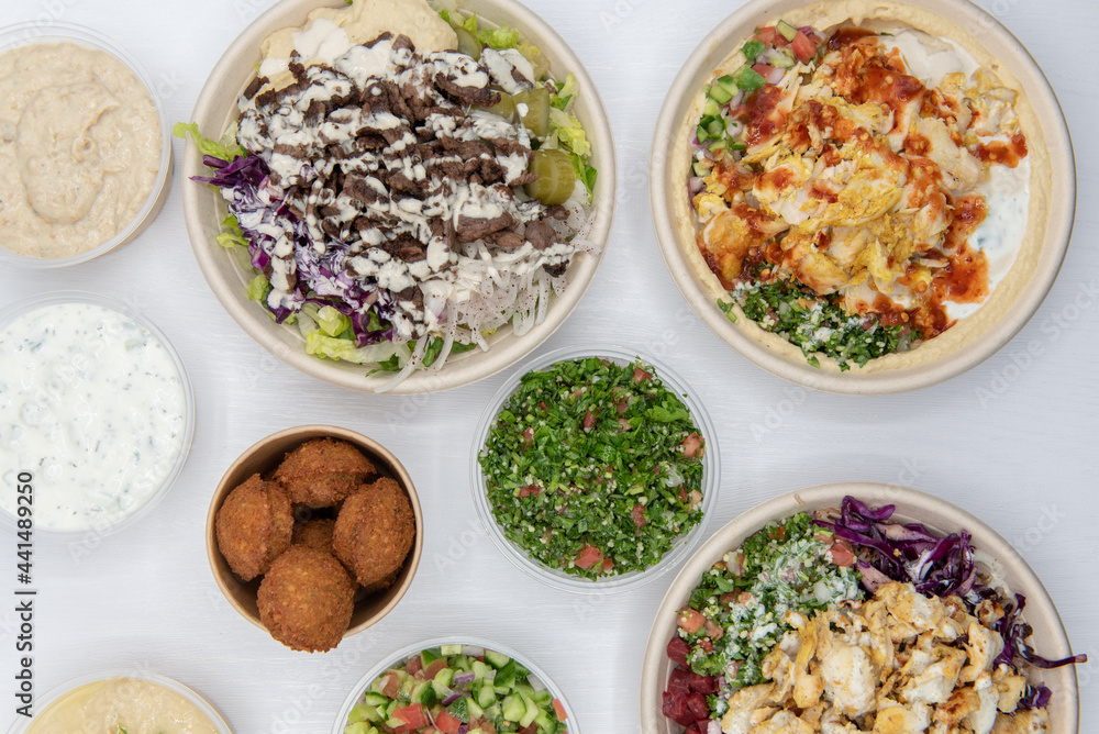 Huge variety of Mediterranean meals on a white table with the bite size falafels on the center of the food Huge variety of Mediterranean meals on a white table with the bite size falafels on the center of the food