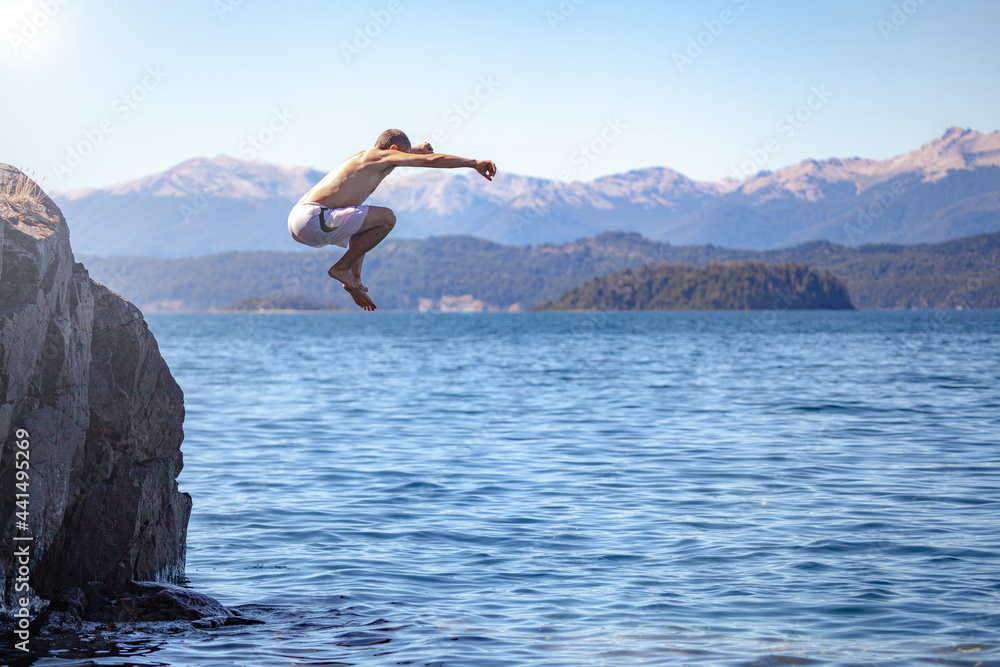 person jumping in the water from a rock. Adventure freedom success happiness risk concept