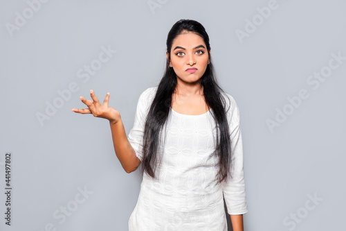Asia Portrait of clueless and indecisive brunette woman with angry expression doubtful and skeptical expression isolated over gray background.