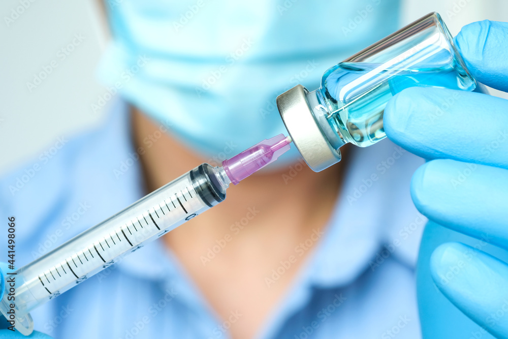 doctor's hand holds a syringe and a blue vaccine bottle at the hospital. Health and medical concepts. doctor's hand holds a syringe and a blue vaccine bottle at the hospital. Health and medical concepts.