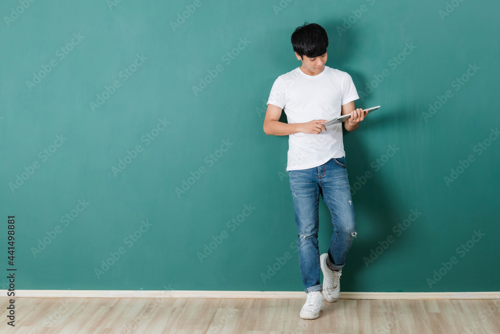 Smiling Asian man holding laptop computer in studio